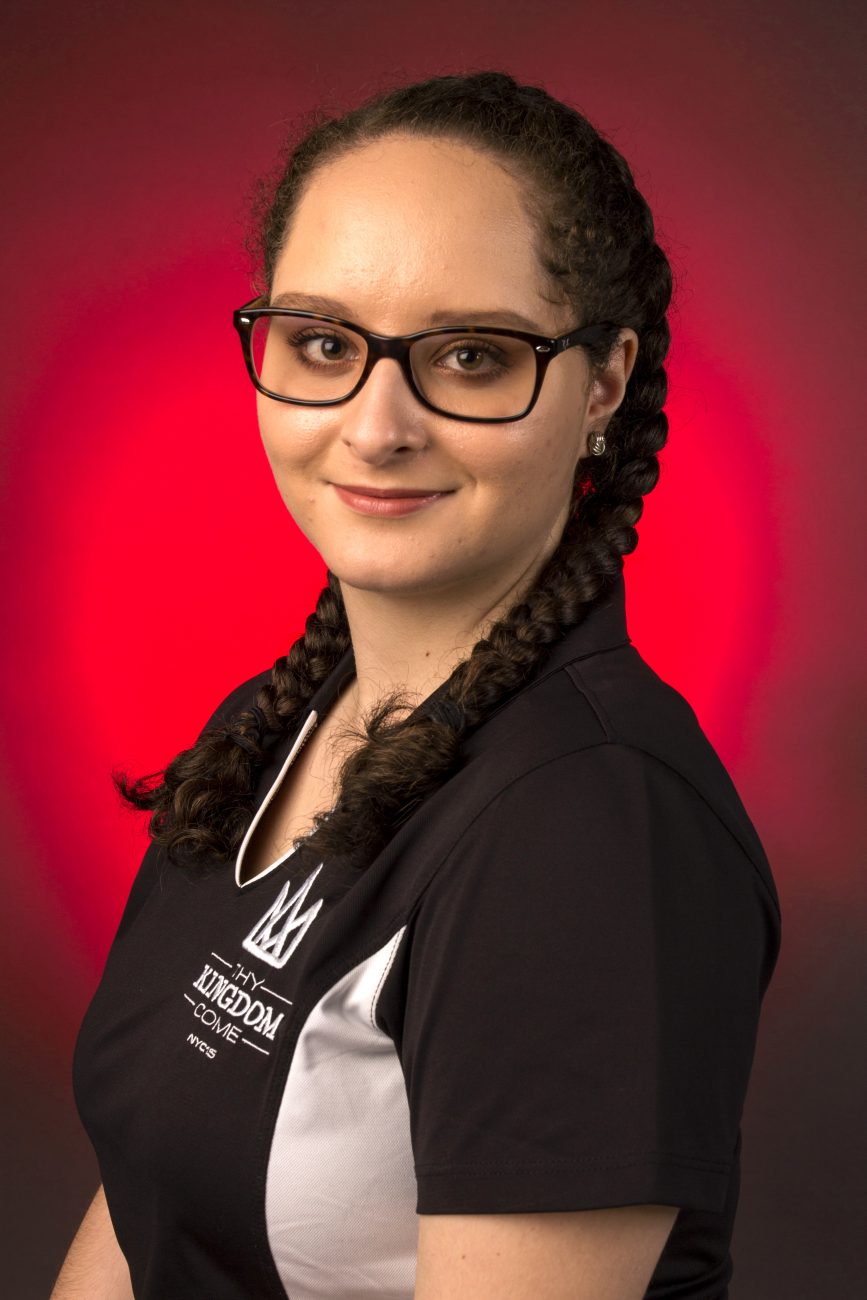 Portrait of Emilisse Ortiz in a black collared shirt against a red backdrop