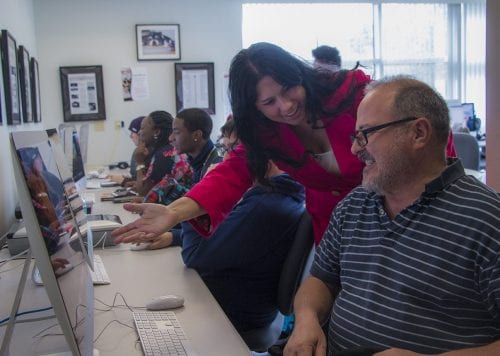 Lab assistant, Rebecca Ruiz, guides a student in the bustling Digital Media lab.
