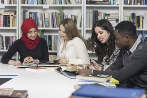 Diverse group of students sitting and studying in library