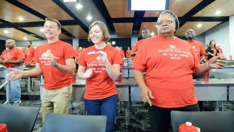 Polk State Student Services employees, from left, Joshua and Sarah Plazak and Sandra Walker do the "Eagle Shuffle at the recent Student Services Retreat.