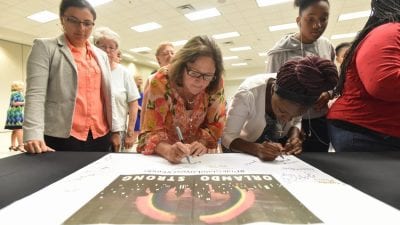 Students and employees sign their names to a banner in support of the Orlando nightclub shooting victims during a memorial event Monday at Polk State Winter Haven.