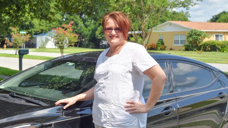 Polk State alumna Amy Eaton stands next to the new car she was able to purchase after graduating from Polk State free of student-loan debt.