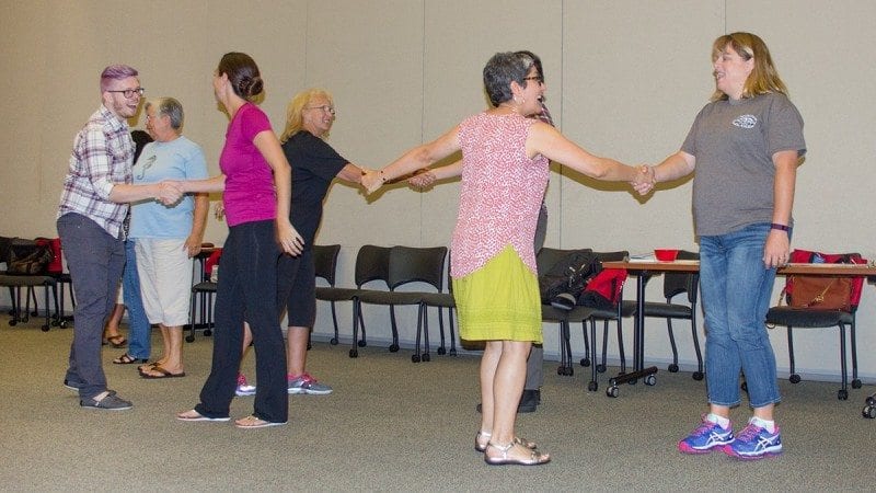 Ilene Fins, second from right, one of the instructors in the Arts Integration Summer Institute, leads teachers in a group handshake, one of the exercises that can be used to get students moving, interacting and excited at the start of the day.