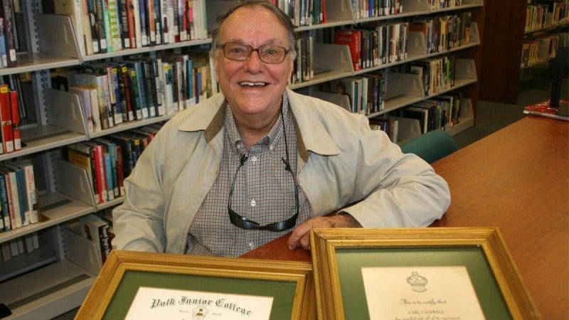 Carl Caldwell graduated from what was then Polk Junior College in 1967. He went on to have a career in accounting. He is shown here at the Dundee Public Library, where he spends much of his time, with his diploma and certificate of induction into Polk's Xi Pi chapter of Phi Theta Kappa.