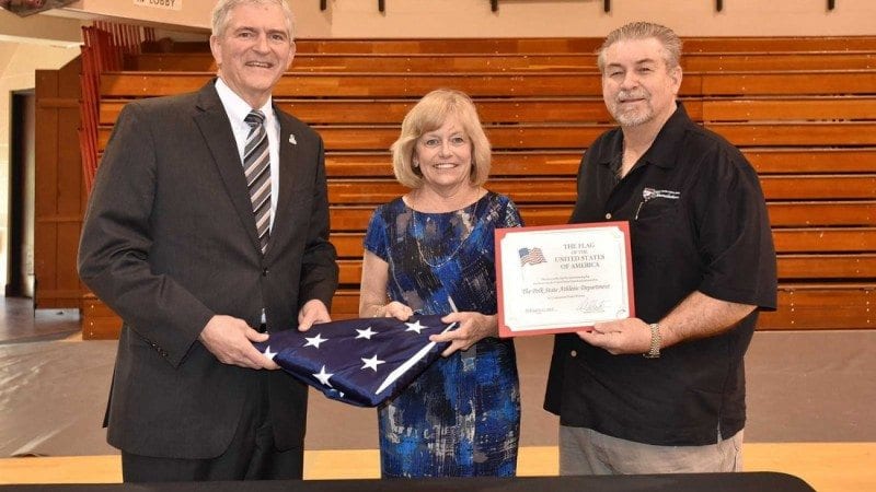 Rep. Daniel Webster (L) presents a flag that was flown over the U.S. Capitol to Polk State President Eileen Holden and Athletic Director Bing Tyus. The flag will be displayed in the Polk State Winter Haven Health Center.