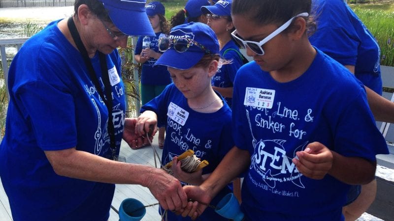 Polk State Earth Science Professor Natalie Whitcomb helps Hook, Line & Sinker for STEM participants collect water samples at Crooked Lake on Saturday.