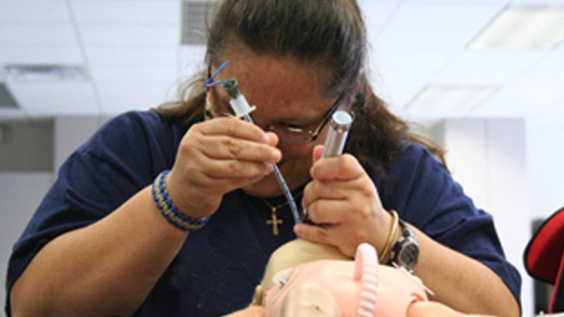 Jeanette Perez travels from Orlando to study in Polk State's EMS program. Here, she practices intubating on an infant mannequin.