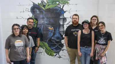 Art students and faculty in front of mural at Denison Middle