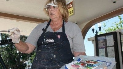 Polk State student Joyce Irwin paints at the Winter Haven bus terminal on Monday as part of Polk Vision's Art In Transit.