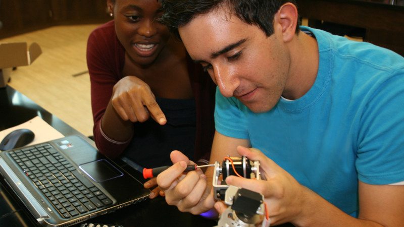 Polk State Chain of Lakes Collegiate High School students and Scholarobotics Academy participants Natalie Weekfell (L) and Randy Esfahani make adjustments to a robotic arm that will be used for microsuturing.